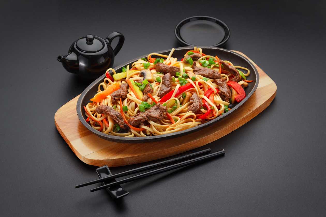 Fried udon noodles with beef on iron stove