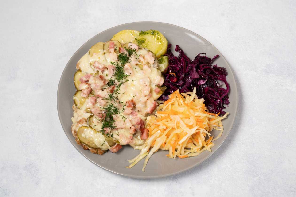 Pork steak baked with bacon bits, vegetables and cheese