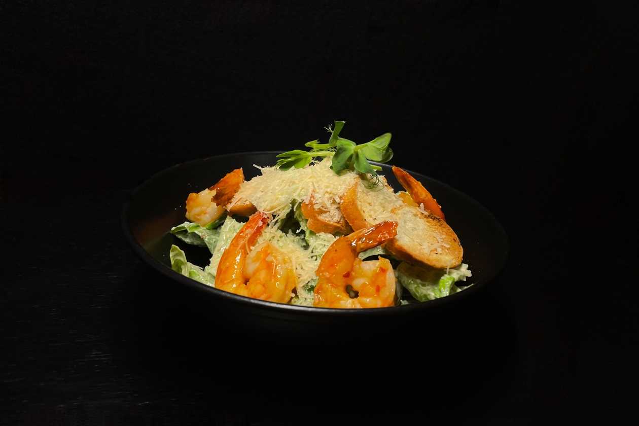 Roman lettuce with caesar dressing and parmesan cheese with tiger prawns