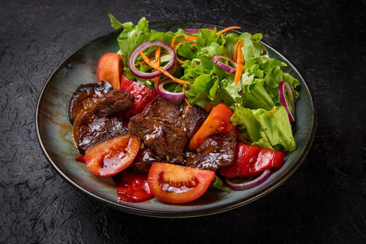 Warm salad with veal, tomatoes, bell peppers, eggplant, zucchini