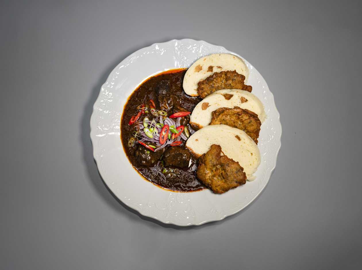 Spicy beef goulash with red onion and potato pancakes/bread dumpling