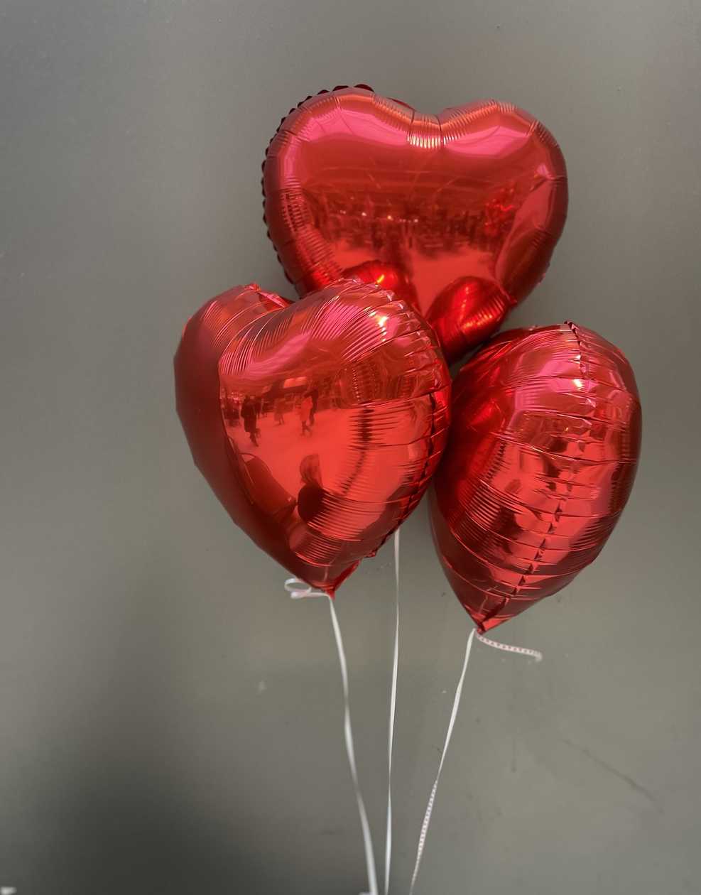 Three heart-shaped balloons filled with helium