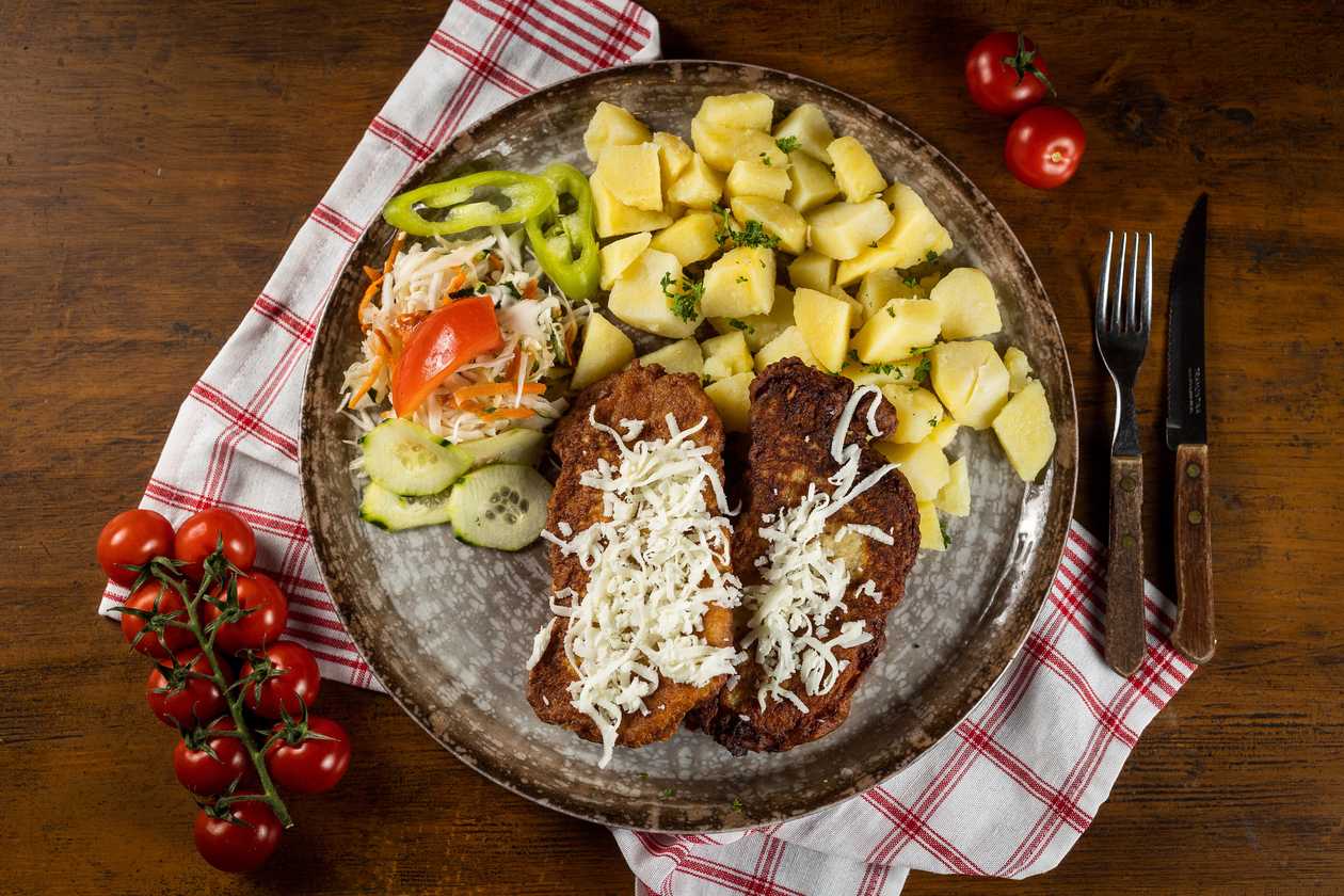 Montenegrin pork schnitzel, cooked potatoes, vegetable garnish