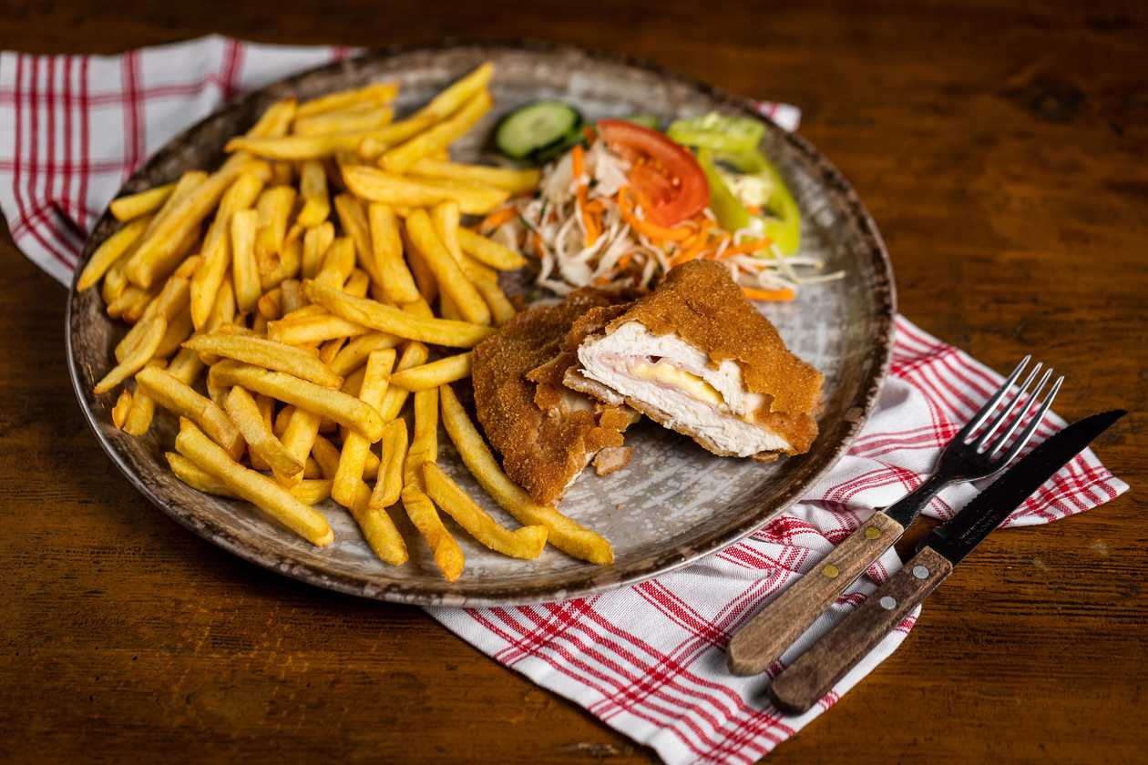 Fried stuffed chicken pocket with ham and cheese, fries, vegetable garnish