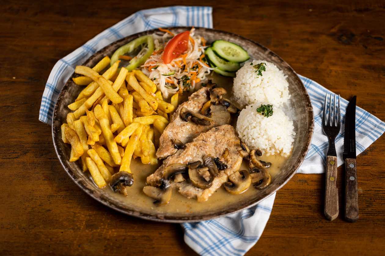 Natural pork schnitzel on champignons, 1/2 rice, 1/2 fries, vegetable garnish