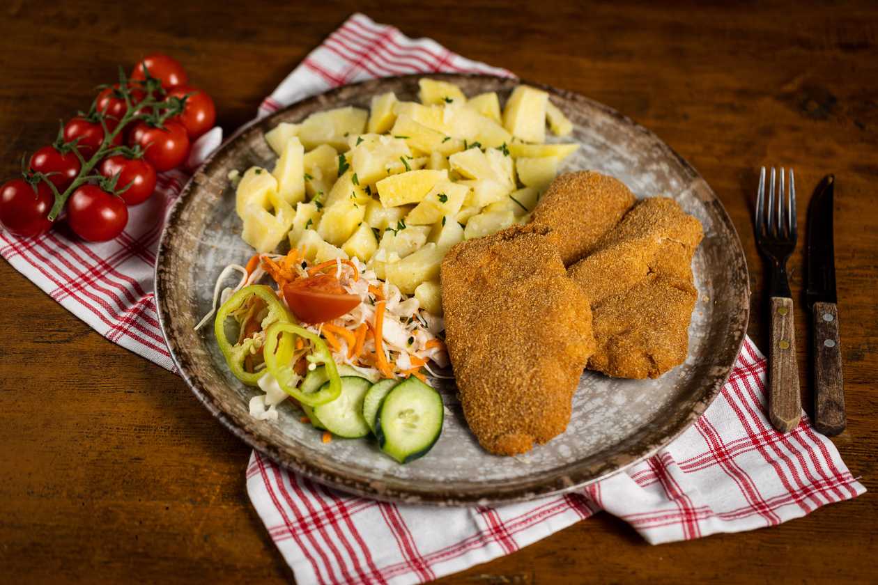 Fried pork schnitzel, cooked potatoes, vegetable garnish