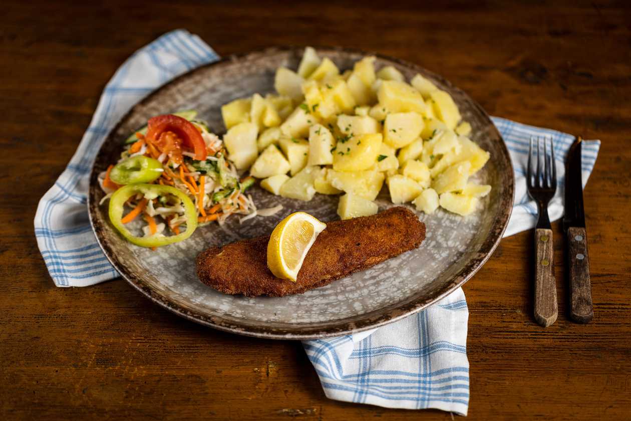 Fried fish fillet, cooked potatoes, vegetable garnish