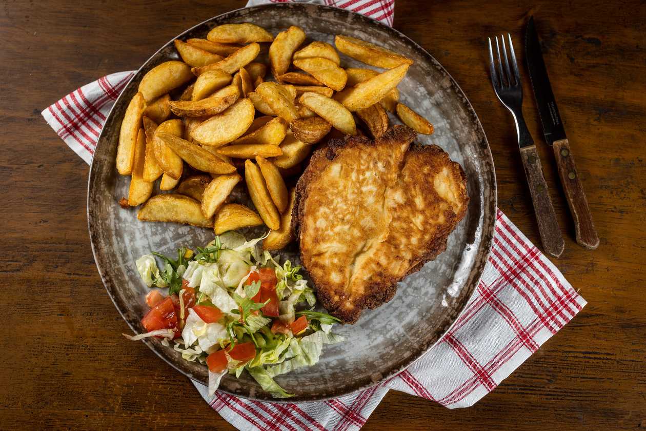 Chicken schnitzel in garlic batter, baked potatoes, vegetable garnish