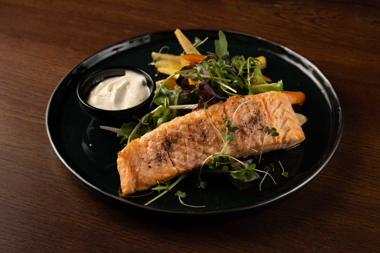Grilled salmon with caramelised root vegetables, baby leaves and blue cheese sauce