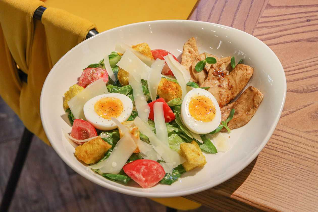 Salad with fried chicken fillet, vegetables, poached egg and Caesar sauce