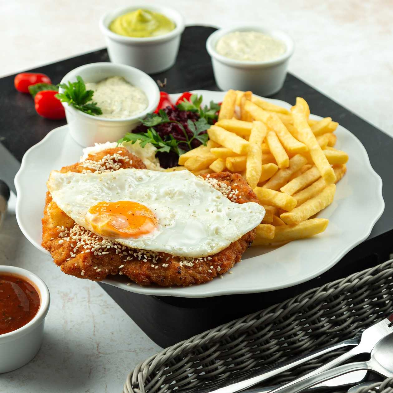 Pork schnitzel with fried egg served with potatoes and seasonal salad