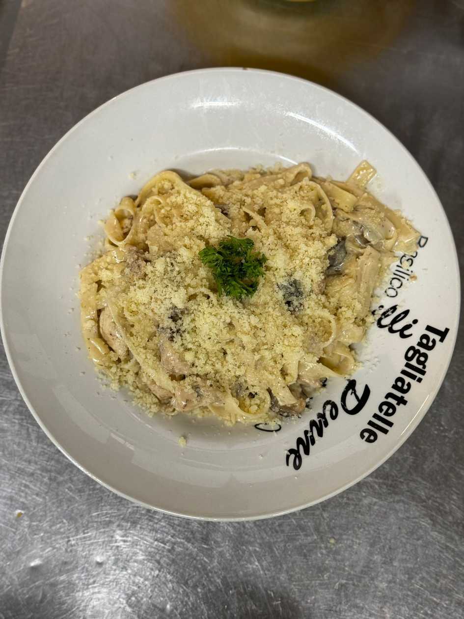 Tagliatelle with chicken and mushrooms in cream sauce topped with parmesan