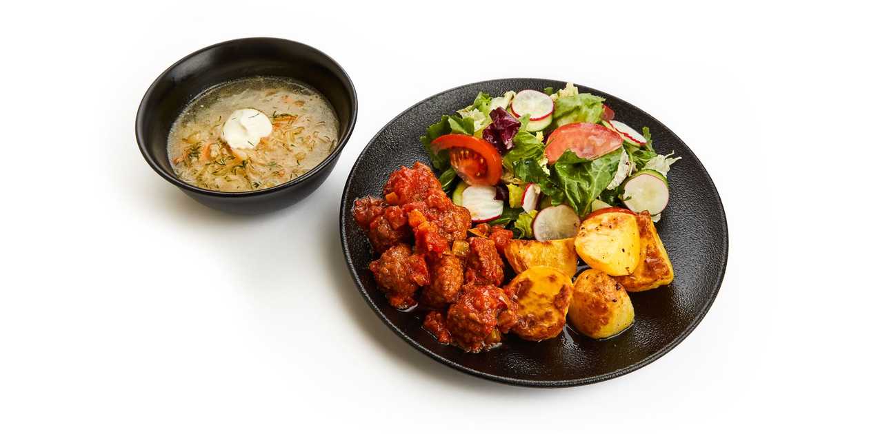 Sauerkraut soup and pork meatballs stewed in tomato sauce with fried potatoes and fresh vegetable salad