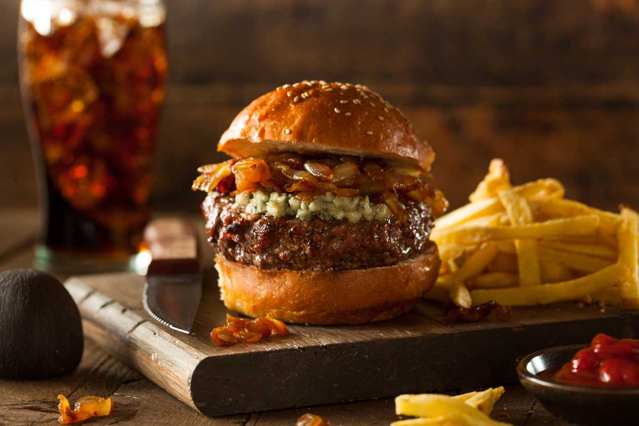 Hovězí Burger s karamelizovanou cibulí, modrým sýrem, BBQ omáčkou, salátem