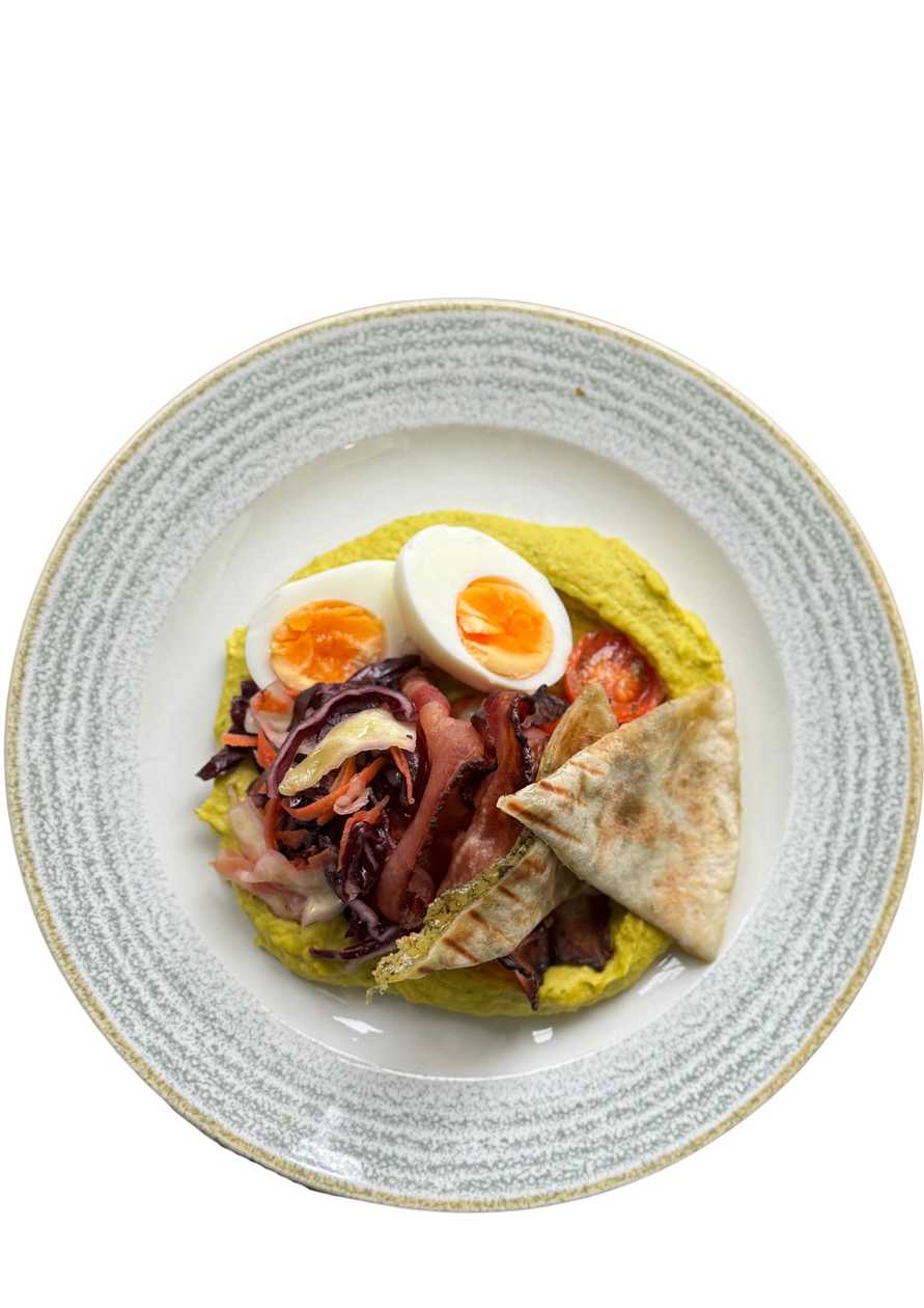Hummus with egg, herb flatbread, coleslaw salad, and crispy bacon.
