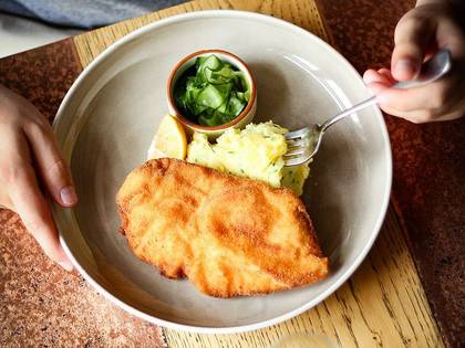 Chicken schnitzel fried in a fresh roll with mashed butter potatoes with chives