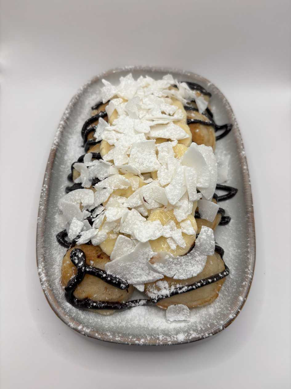 Minipancakes with hot chocolate sauce, banana, coconut flakes and mascarpone