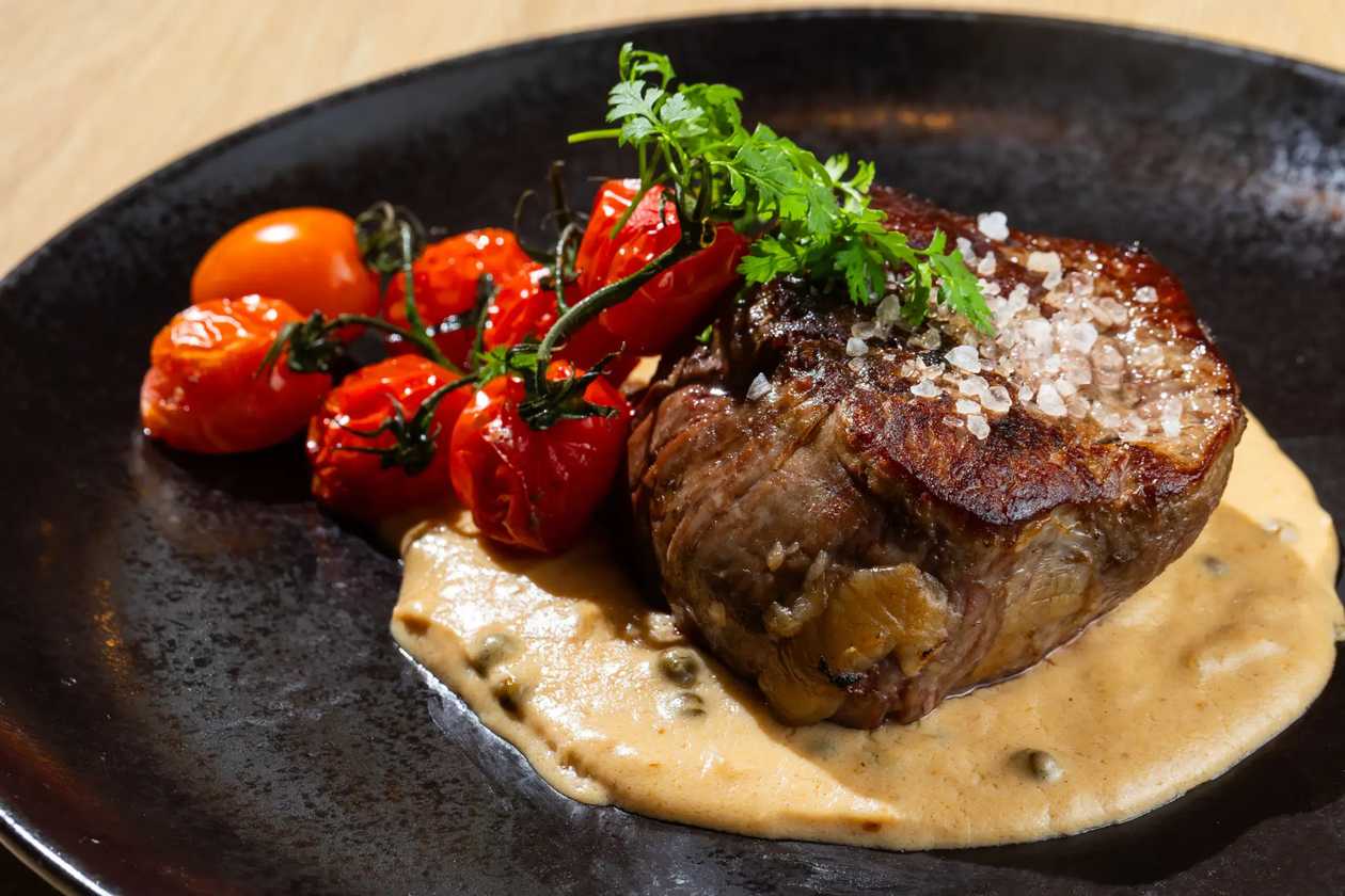 Beef Steak from aged Argentinian tenderloin, grilled with coarse sea salt, served with pepper sauce, grilled cherry tomatoes, and rosemary roasted potatoes