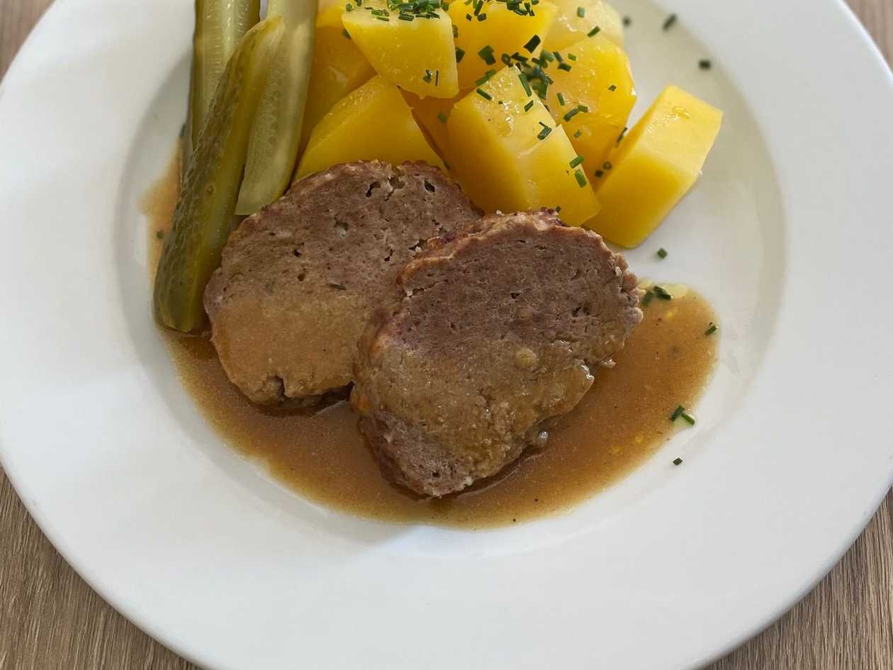 1.) Domácí sekaná pečeně podávaná s vařeným pažitkovým bramborem a kyselou okurkou