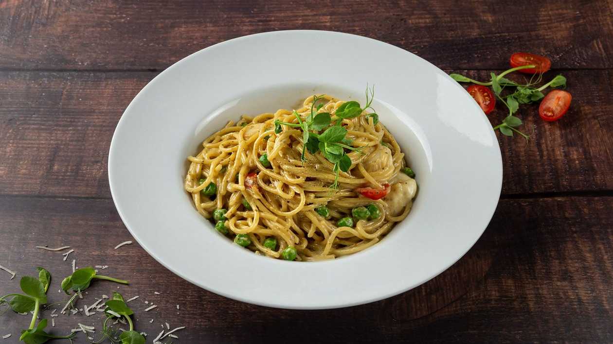 Spaghetti with mozzarella cheese, green peas and cherry tomatoes