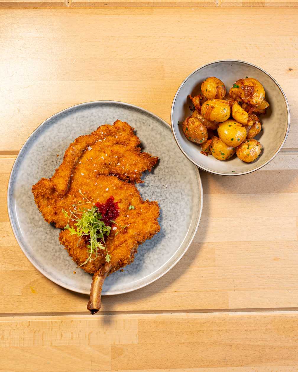 Fried pork tomahawk steak, confit baby potatoes, cranberry