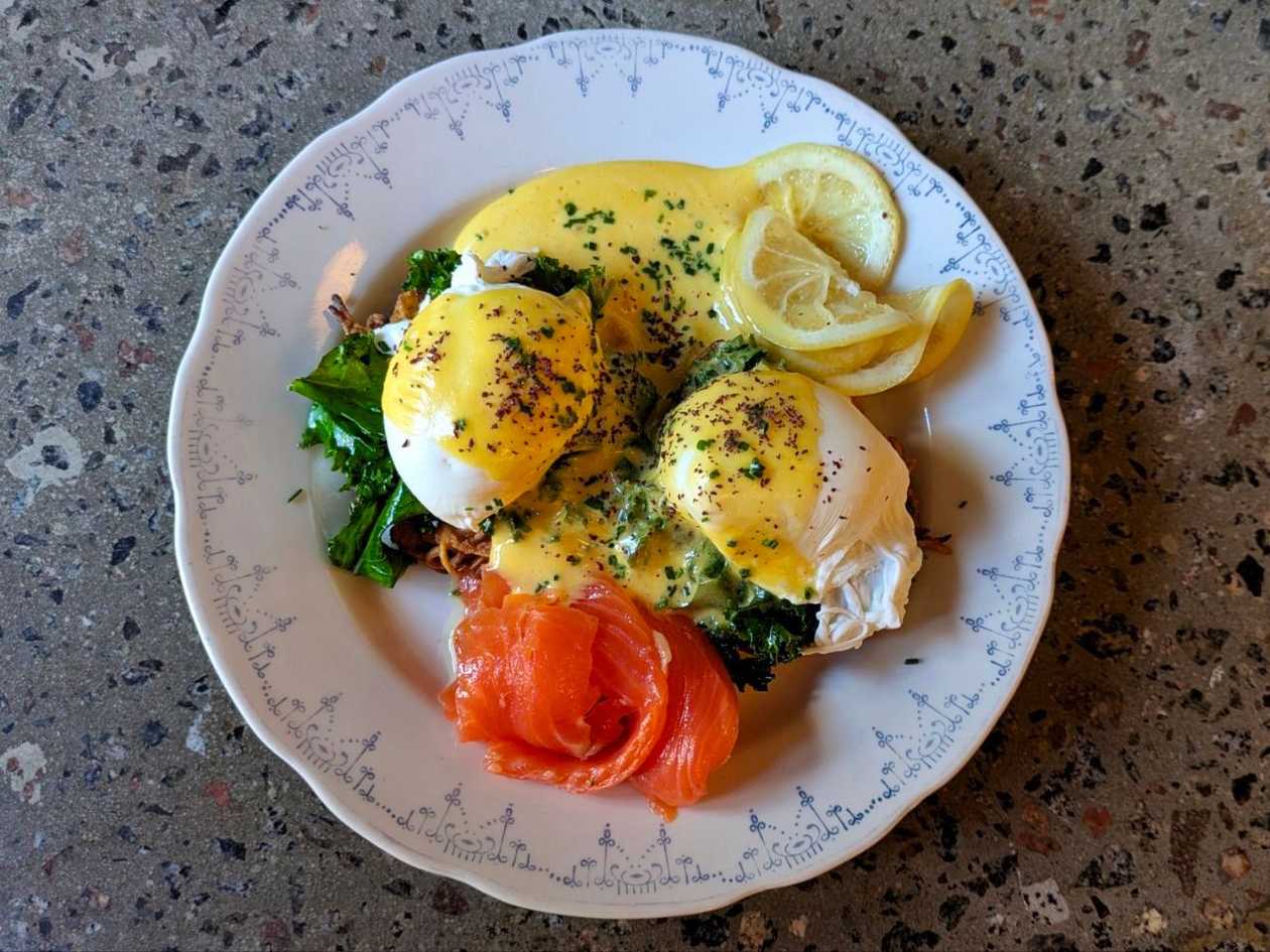 Eggs Benedict with potato and fresh corn pancake, kale, hollandaise sauce with ponzu and chives