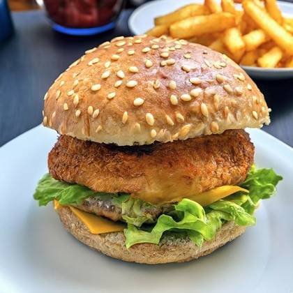 CHICKEN burger served in a homemade bun with baked bacon, camembert and tomatoes and sauce of your choice