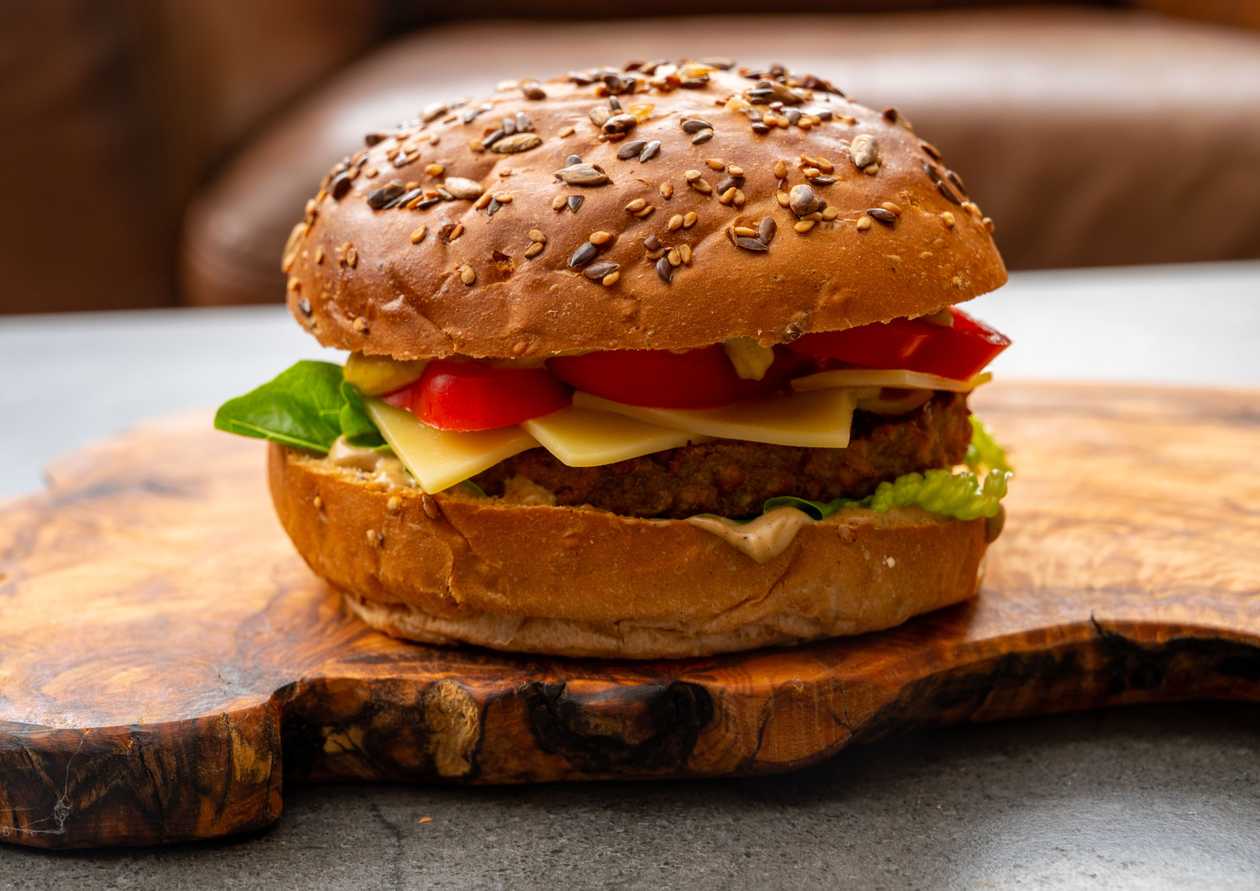 CHEESE burger served in a homemade bun with lettuce and tomato, topped with homemade tartar sauce