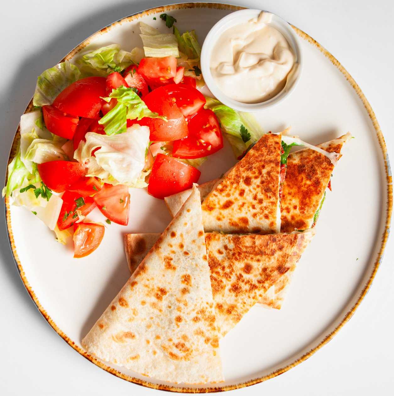 Tortillová placka zapečená se sýrem a sušenými rajčaty, rukola, zakysaná smetana