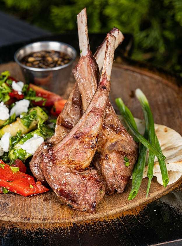 Rack of lamb with grilled vegetables, Feta cheese and Narsharab sauce, served on pita bread