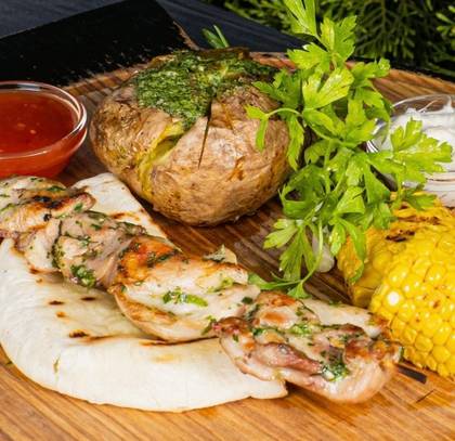 Chicken Skewers with Baked Potatoes, Herb Butter, Grilled Corn, Two Sauces, Served on Pita Bread