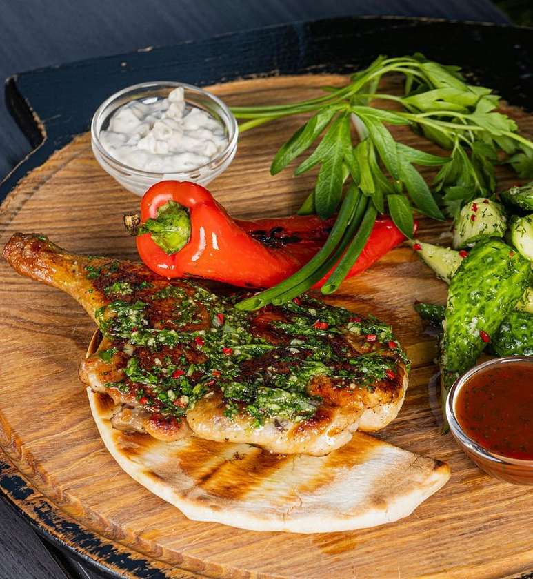 Half Chicken with Grilled Pepper, Quick Pickled Cucumbers, Two Sauces, Served on Pita Bread