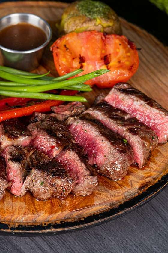 Ribeye Steak with Baked Potato, Herb Butter, Grilled Pepper and Tomato, and Two Sauces