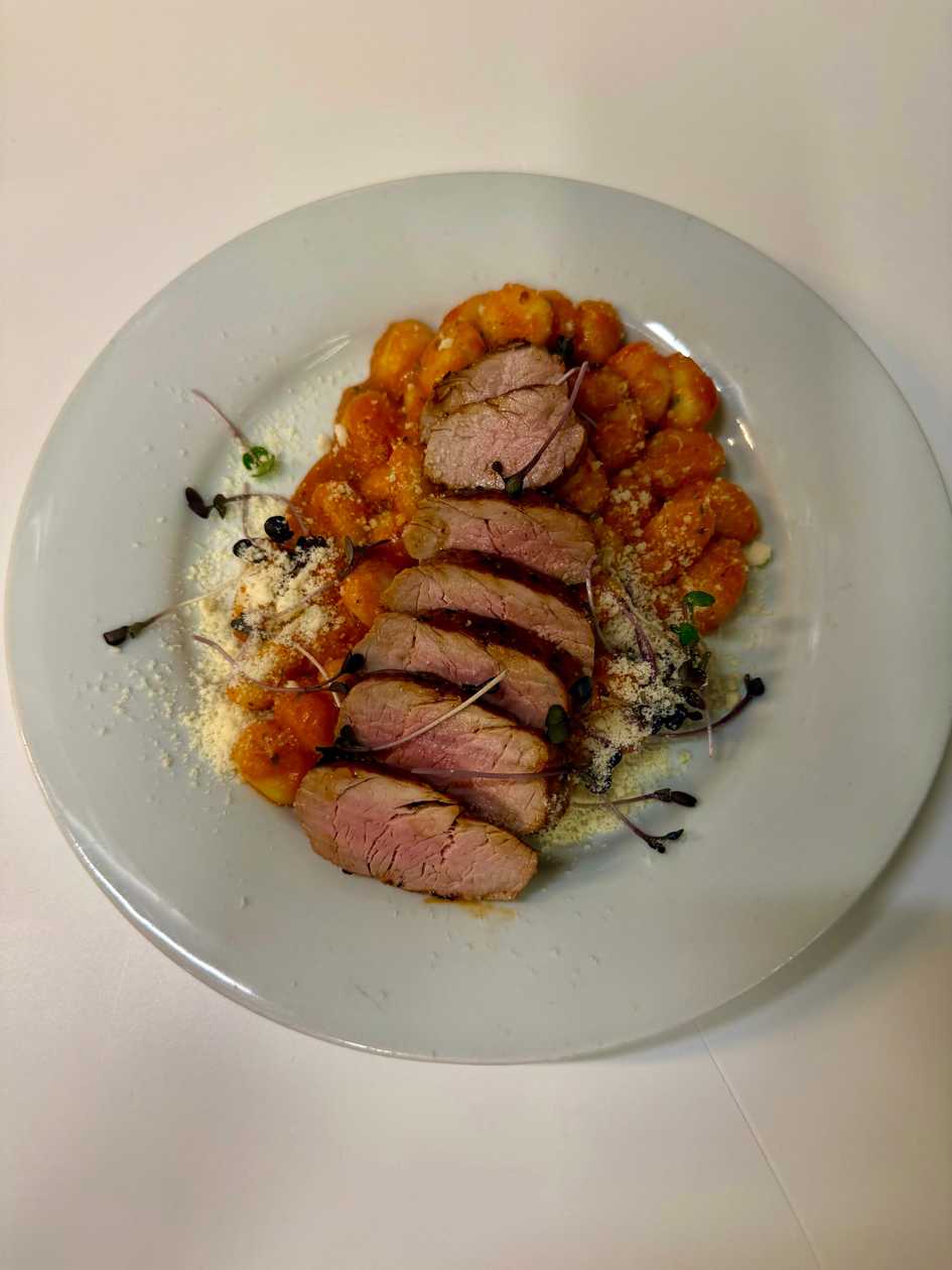 Gnocchi with grilled pork tenderloin, tomato sauce, and Parmesan cheese