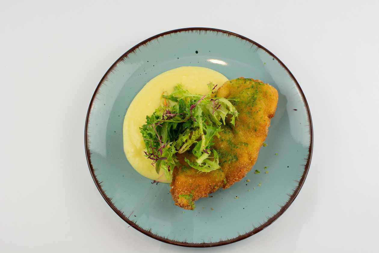 200g Smažený kuřecí řízek s bylinkovým máslem, máslová bramborová kaše