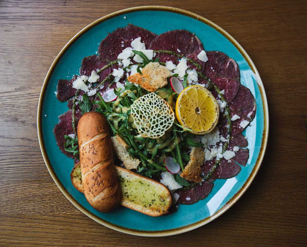 100g Hovězí carpaccio - tenké plátky hovězí svíčkové, rukola, parmezánu a bylinková bagetka
