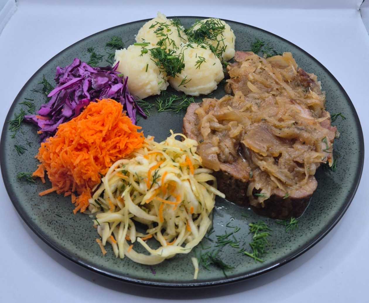 Karkówka pieczona podawana z duszoną cebulką podawana z puree ziemniaczanym i bukietem surówek