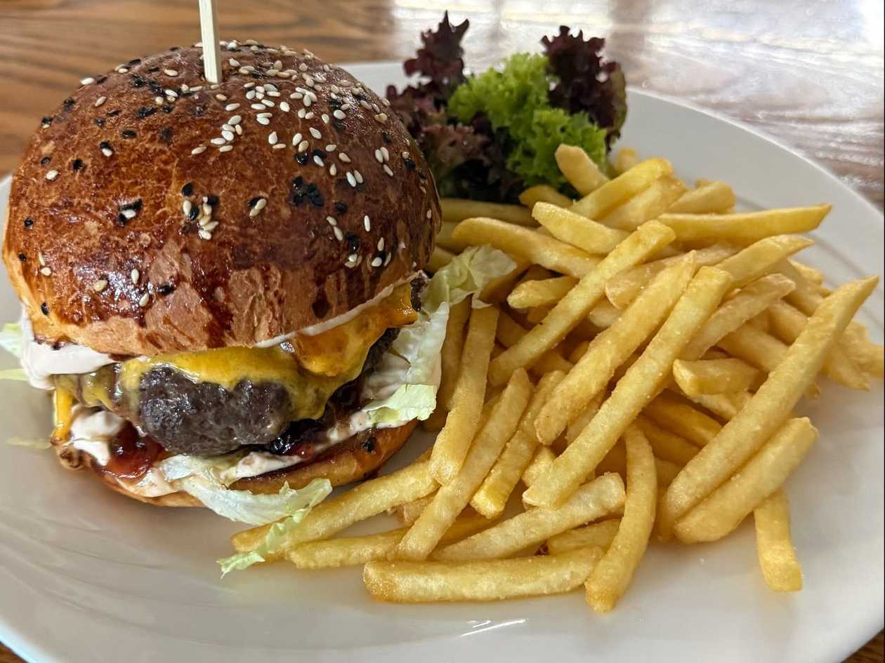 Hovězí burger se slaninou, sýrem cheddar, ledový salát s cibulovým chutney v naší domácí briošce s hranolkami