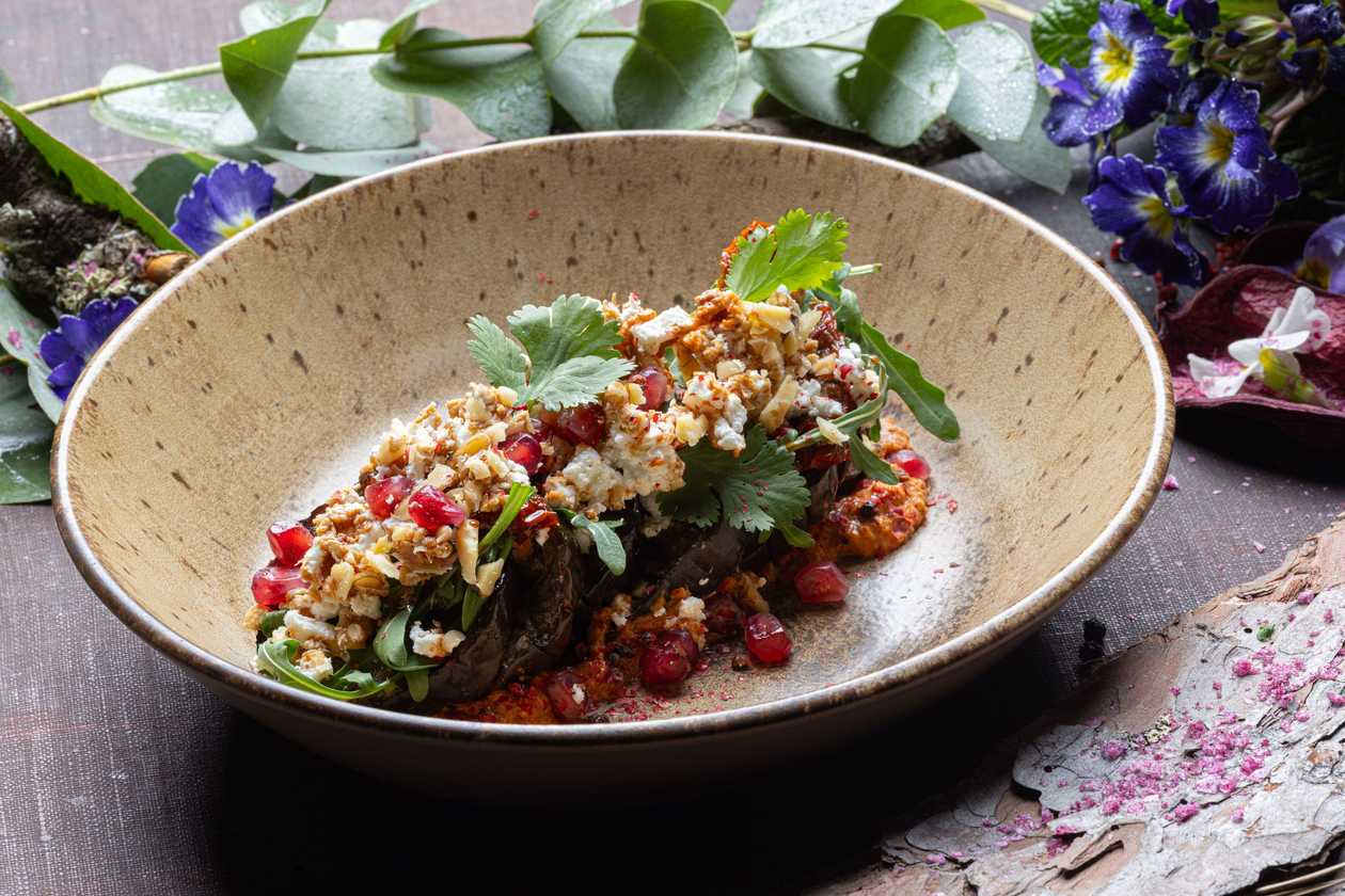 Küpsetatud baklažaan paprika-sotéga, fetajuustu, värskete ürtide, granaatõuna ja kreeka pähklitega