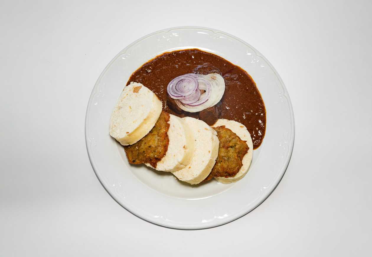 Beef goulash with bread dumplings, potato pancakes and fresh onion