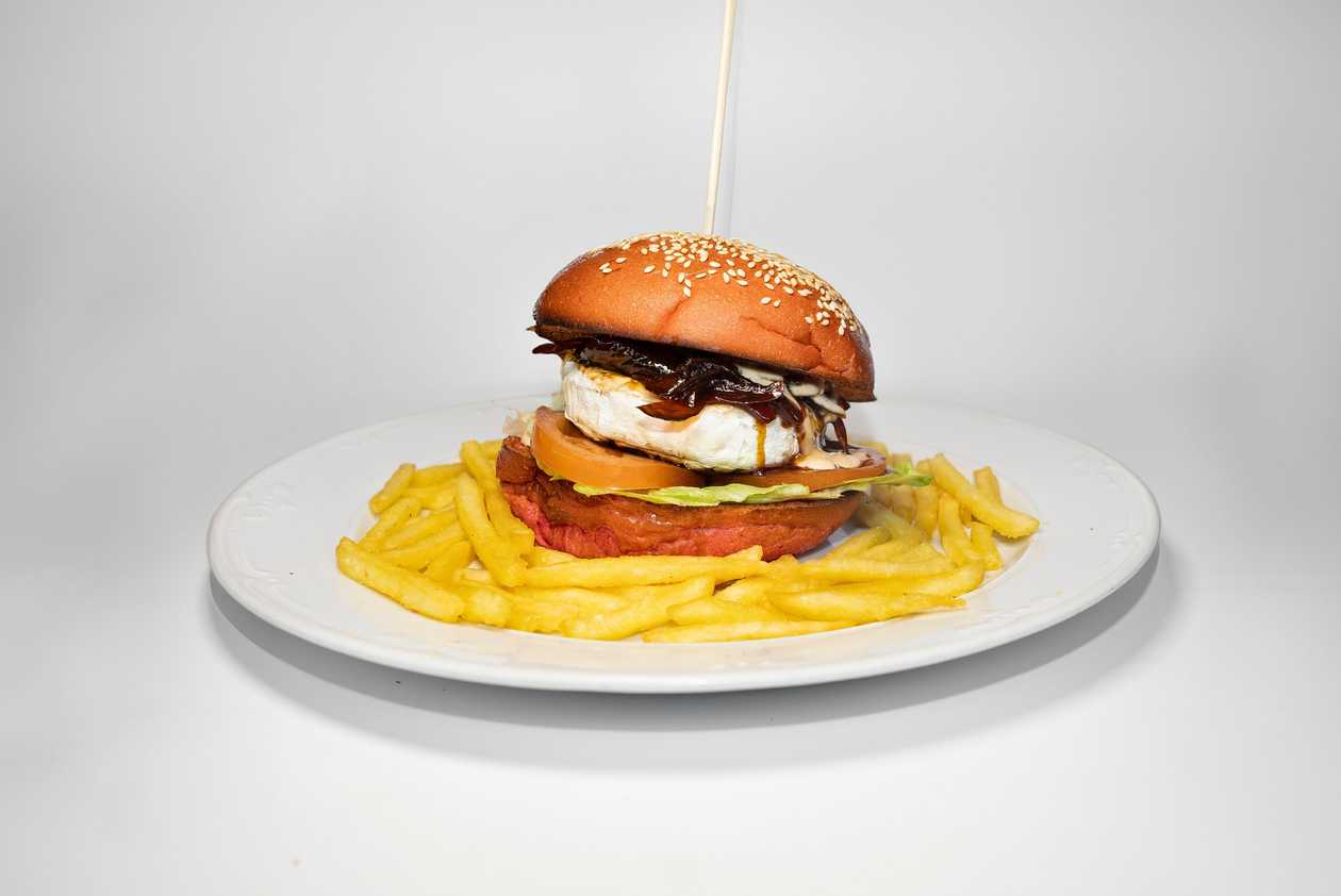 Hamburger from grilled camembert, BBQ sauce, mayonnaise, tomato, salad and caramelized onion, french fries