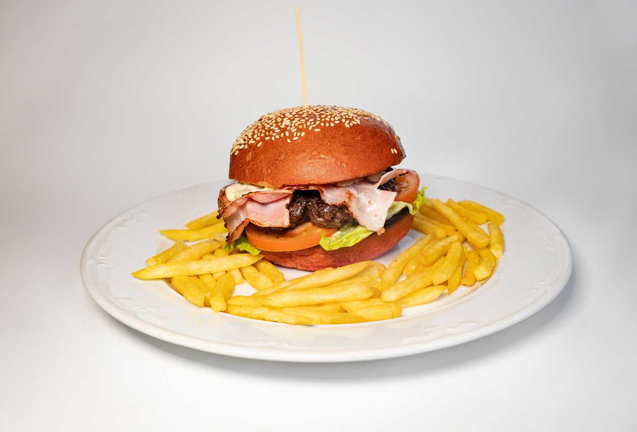 Beef hamburger with herb mayonnaise, fried bacon, tomato and lettuce, french fries