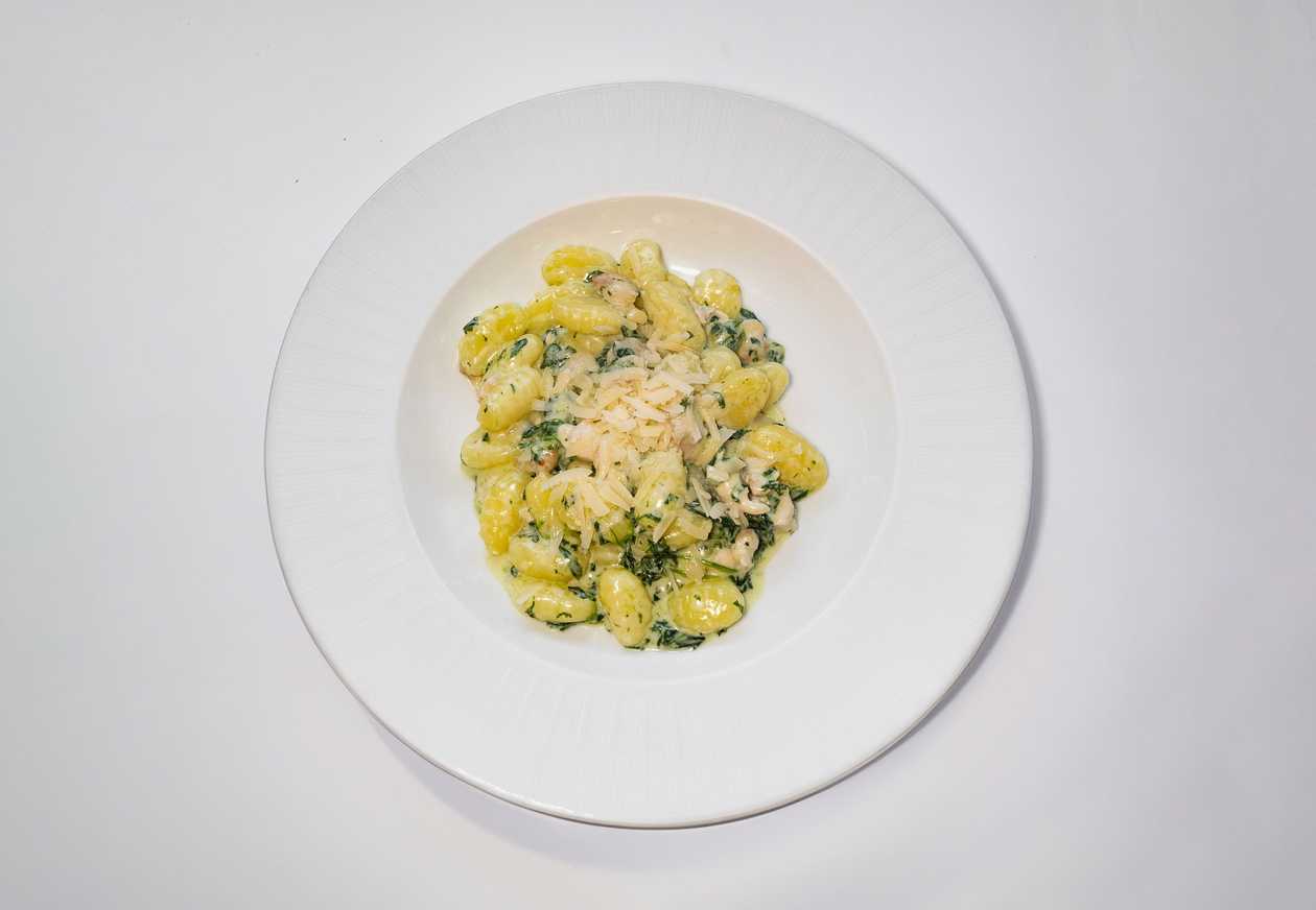 Gnocchi with pancetta, cream sauce, spinach and garlic, sprinkled with grana padano cheese