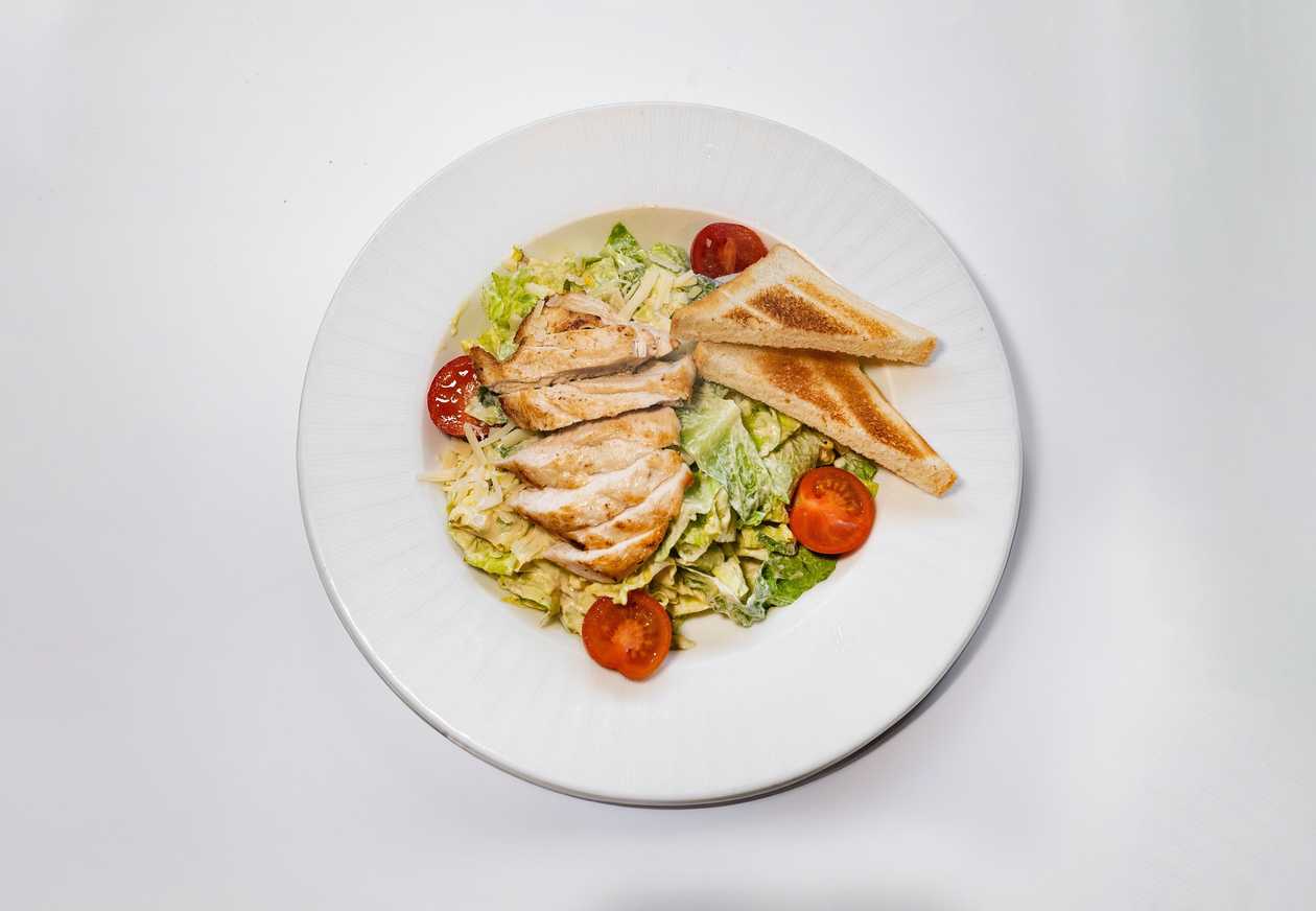 Salad Caesar with grilled pieces of chicken, parmesan cheese, toast and cherry tomatoes