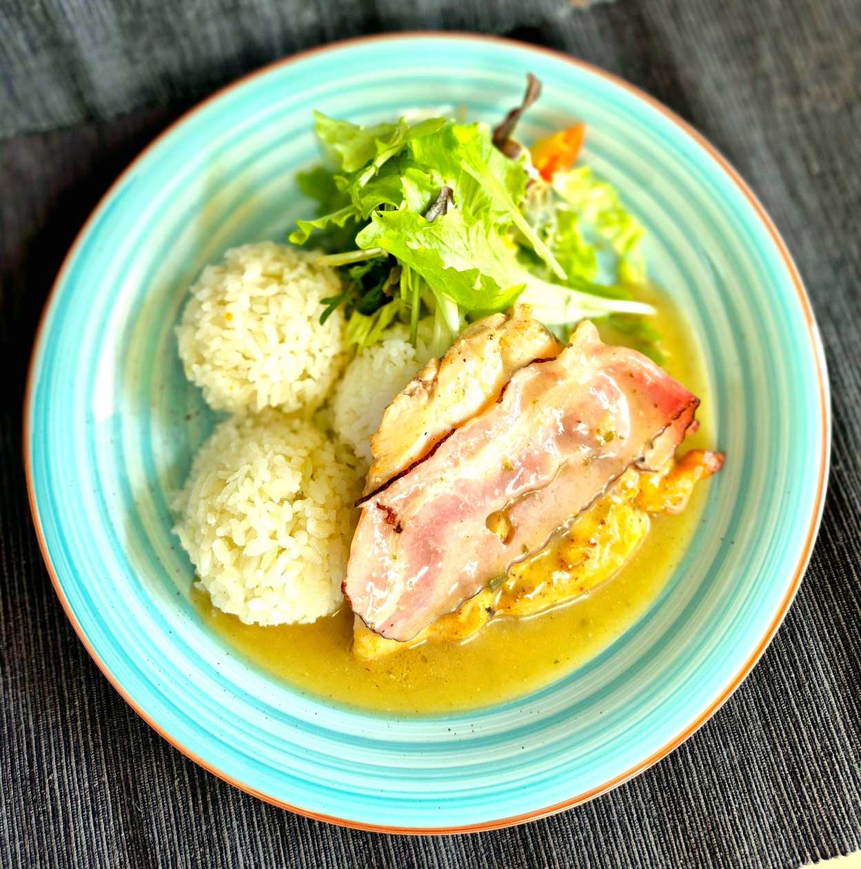 Chicken breasts wrapped in bacon with sage sauce, served with steamed rice and mixed leaf salad