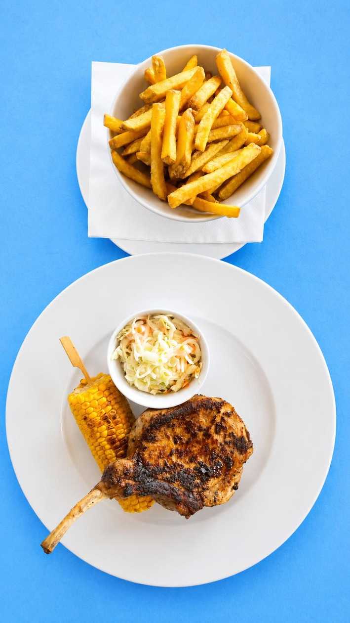 Grilovaný vepřový tomahawk, kukuřičný klas, hranolky, Coleslaw