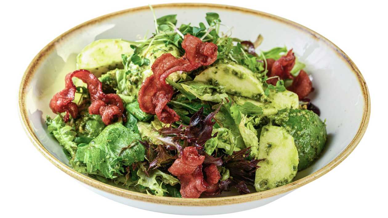 Lettuce salad with avocado, mozzarella, basil pesto, and crispy bacon