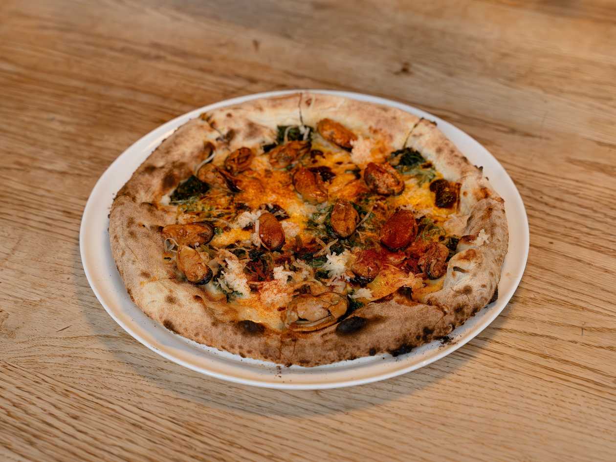 Pizza with mussels, pickled spinach and a mix of cheeses
