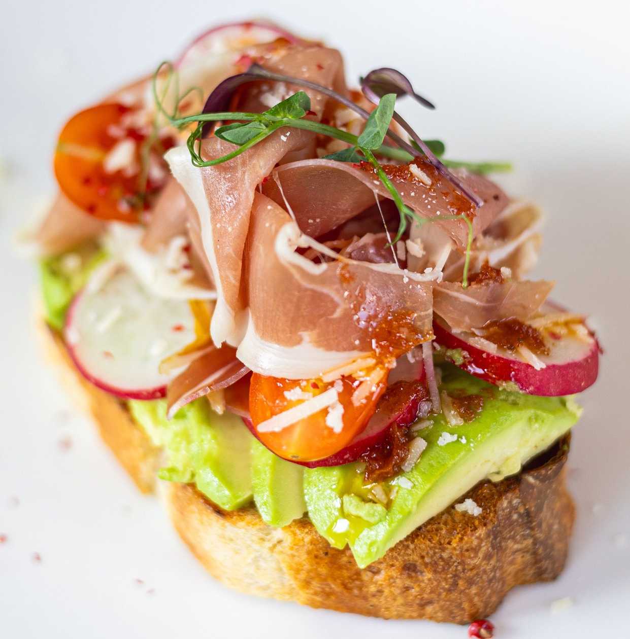 Bruschetta with Prosciutto, Avocado, Cherry Tomatoes, Radishes, Parmesan, and Sun-Dried Tomato Pesto