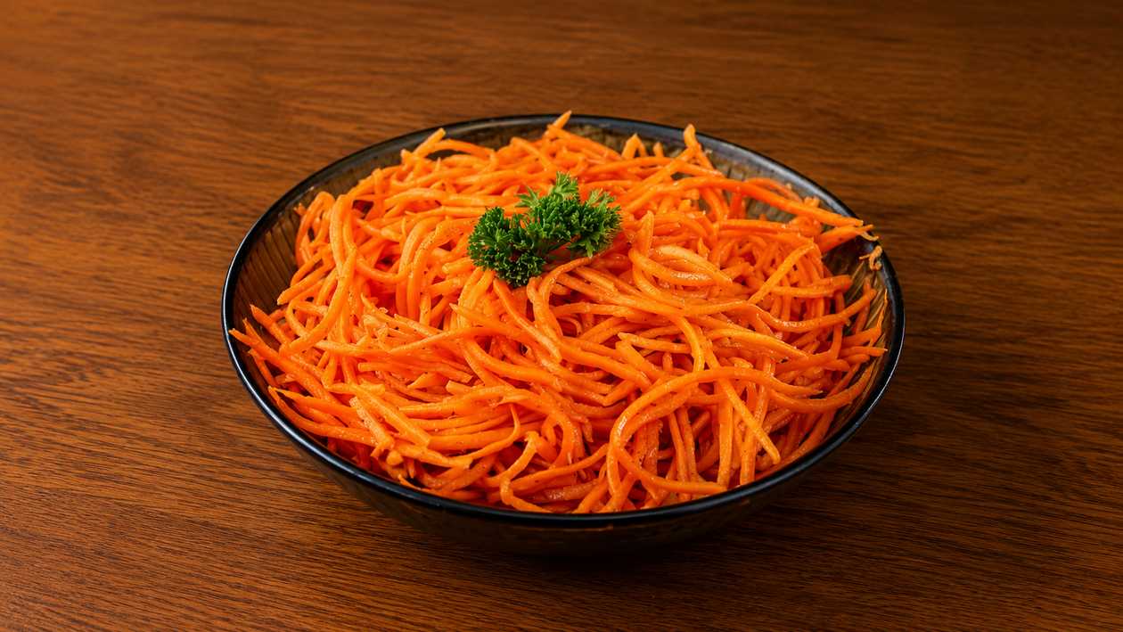 Mrkev po korejsku Tradiční pikantní salát z jemně strouhané mrkve marinované v aromatickém dresinku z česneku, octa a rostlinného oleje, dochucený koriandrem a jemně pálivým kořením